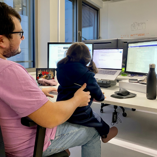 Matias and his two-year old daughter on his lap on his computers 